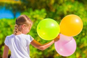 Adorable little girl playing with balloons at the beach photo