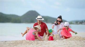 familia haciendo castillos de arena en la playa blanca tropical video