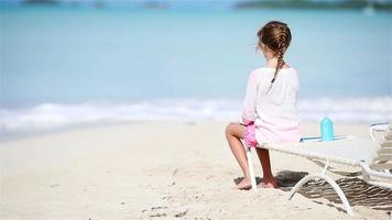 klein meisje geniet van tropische strandvakantie op zonnebank kijkend naar de zee video