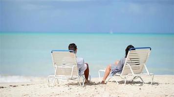 família de dois relaxando em espreguiçadeiras apreciando a vista para o mar e suas férias