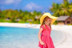 Adorable little girl in hat at beach during summer vacation photo