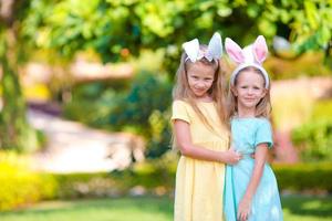 dos adorables hermanitas con orejas de conejo el día de pascua al aire libre foto