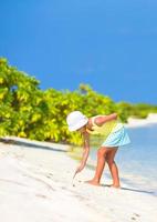 Little girl drawing on sandy beach photo