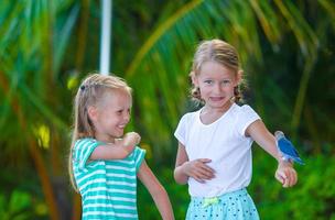 Adorable happy girls at beach with colorful little bird photo