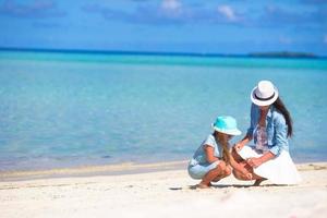 Mother and baby girl drawing on sandy beach photo