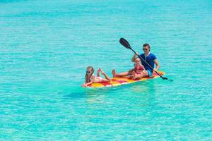 niñas pequeñas y papá joven en tabla de surf durante las vacaciones de verano foto