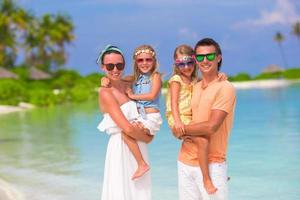 joven familia de cuatro en vacaciones en la playa foto