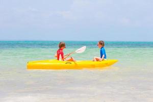 Little adorable girls enjoying kayaking on yellow kayak photo