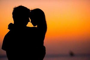 Little girl and dad silhouette in the sunset at the beach photo