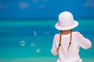 Adorable little girl making soap bubbles during summer vacation photo