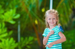 adorable niña feliz en la playa con colorido pajarito