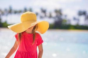 Adorable little girl in hat at beach during summer vacation photo