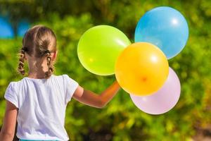 Adorable little girl playing with balloons at the beach photo