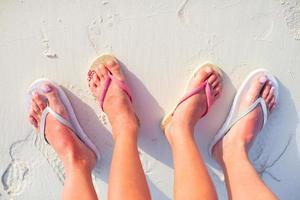 Closeup mother and kid feet on white sand beach photo