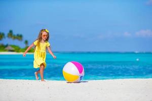 Little adorable girl playing on beach with ball photo