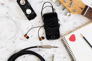 Music stuff. Guitar, guitar pedal, headphone, mobile phone on white background. Top view. Flat lay photo