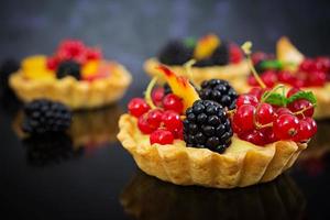 Tartlets with different berries on dark background photo