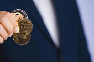 Golden bitcoin coin Dogecoin DOGE, Ethereum ETH group included with Cryptocurrency on hand business man wearing a blue suit. Filed and put and give to me. Close up and Macro photography concept. photo