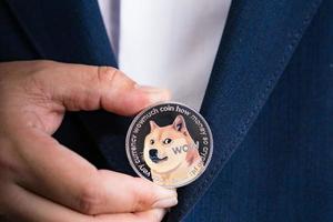 Golden bitcoin coin Dogecoin DOGE group included with Cryptocurrency on hand business man wearing a blue suit. Filed and put and give to me. Close up and Macro photography concept. photo