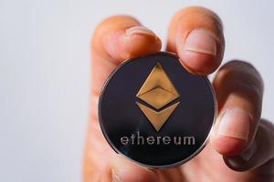 close up shot Golden Ethereum ETH included with Cryptocurrency on hand business man wearing a blue suit. Filed and put and give to me on white background and free space to place the text something. photo