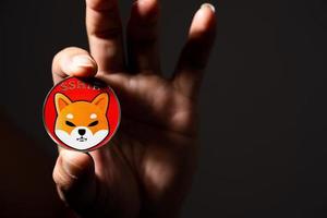 Hand or fingers picking Shiba coin included with Crypto currency coin Dogecoin DOGE in the shadows black room symbol Virtual blockchain technology future is digital money close up and Macro. photo