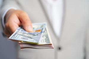 Focus select and blur Foreground Business man and money in us dollar hold on hand wearing a brown suit jacket and Give to me USD, Pay, exchange money vietnamese on white background. photo