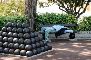 MONTE CARLO, MONACO, 2006. Man asleep in the shade next to a pile of canon balls photo