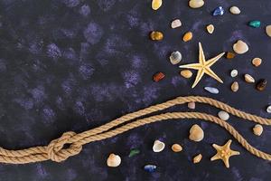concha, estrella de mar y cuerda sobre fondo oscuro. vista superior foto