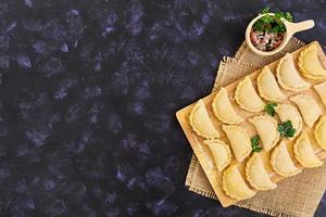 Delicious dumplings with cabbage on dark background. Top view photo