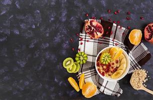 Healthy breakfast. Oatmeal with fruit on dark background. Top view photo
