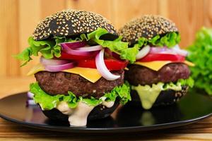 Handmade burger on wooden background. Delicious black burger photo