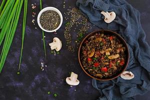 Delicious lentils with pepper and mushrooms on dark background photo