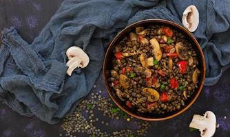 Delicious lentils with pepper and mushrooms on dark background photo