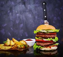 Delicious handmade burger on dark background. Close view photo