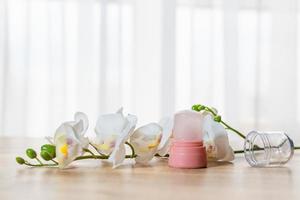 Natural eco crystal alum deodorant and orchid branch with flowers on light wooden background photo