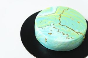 Close-up of mousse cake covered blue and green mirror glaze. French dessert. Frozen mirror icing on the cake. Baking and confectionery concept