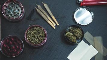 Marijuana buds, joints, paper and lighter lie on dark grey background. photo