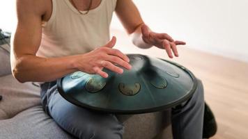 Close up of man hands playing hang drum indoors. Unusual music instrument. photo