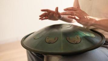 Close up of man hands playing hang drum indoors. Unusual music instrument. photo