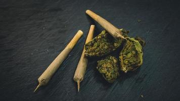 Marijuana buds and joint lie on a dark gray background. photo