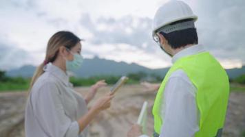 Asian male engineer and young female investor discussing about construction project, Real Estate Building plain land site, looking at digital tablet for work quotations  price detail, project planner video