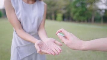 jovem amigo dá um ao outro spray higienizado para as mãos, desinfetando as mãos e a superfície contaminada, proteção contra vírus infecciosos, limpeza lavando as mãos, conscientização sobre higiene pessoal, spray de álcool video