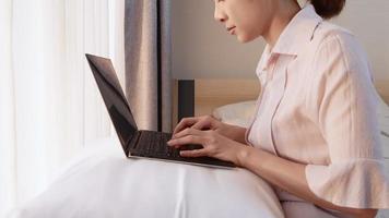 primer plano hermoso trabajador escribiendo en el teclado de la computadora portátil, trabajo desde el concepto de casa, mujer trabajadora, respondiendo correos electrónicos escribiendo documentos o planeando en el software de la computadora, trabajando en la cama, usando una computadora portátil video