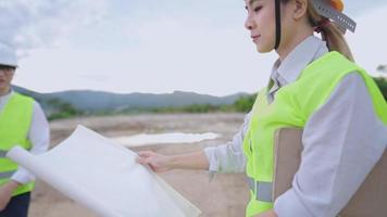 Young female engineer project employee looking at structural blueprints paper, structure planner real estate worker, safety first, outdoor construction site, manufacture, independence hard worker lady video