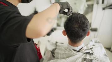 ci-dessus, un homme asiatique se fait couper les cheveux. pendant la période de verrouillage de la quarantaine, lame de rasoir pour tondeuse à cheveux électrique, barbier de gars pendant la pandémie du monde des affaires de réouverture du virus corona covid-19, vue arrière supérieure video