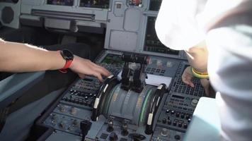 immagine ravvicinata dell'equipaggio di volo che opera su aeromobili commerciali, ripresa all'interno del pannello di controllo del ponte di volo della cabina di pilotaggio, capitano e copilota dell'aeroplano che discutono della rotta di volo, tecnico del sistema dell'aeroplano, video