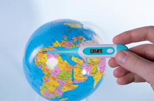 mano que sostiene el termómetro digital sobre un globo