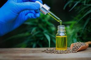 Hand pouring oil into a glass bottle. Hemp oil product. Hemp extract, CBD oil, medical marijuana concept