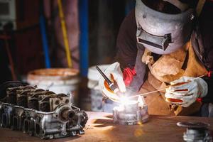 The man in the face mask is welded by argon welding. Welder industrial worker welding with argon machine.
