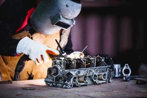 The man in the face mask is welded by argon welding. Welder industrial worker welding with argon machine. photo